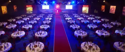 image of arena set with multiple round tables and a red carpet running towards the stage.