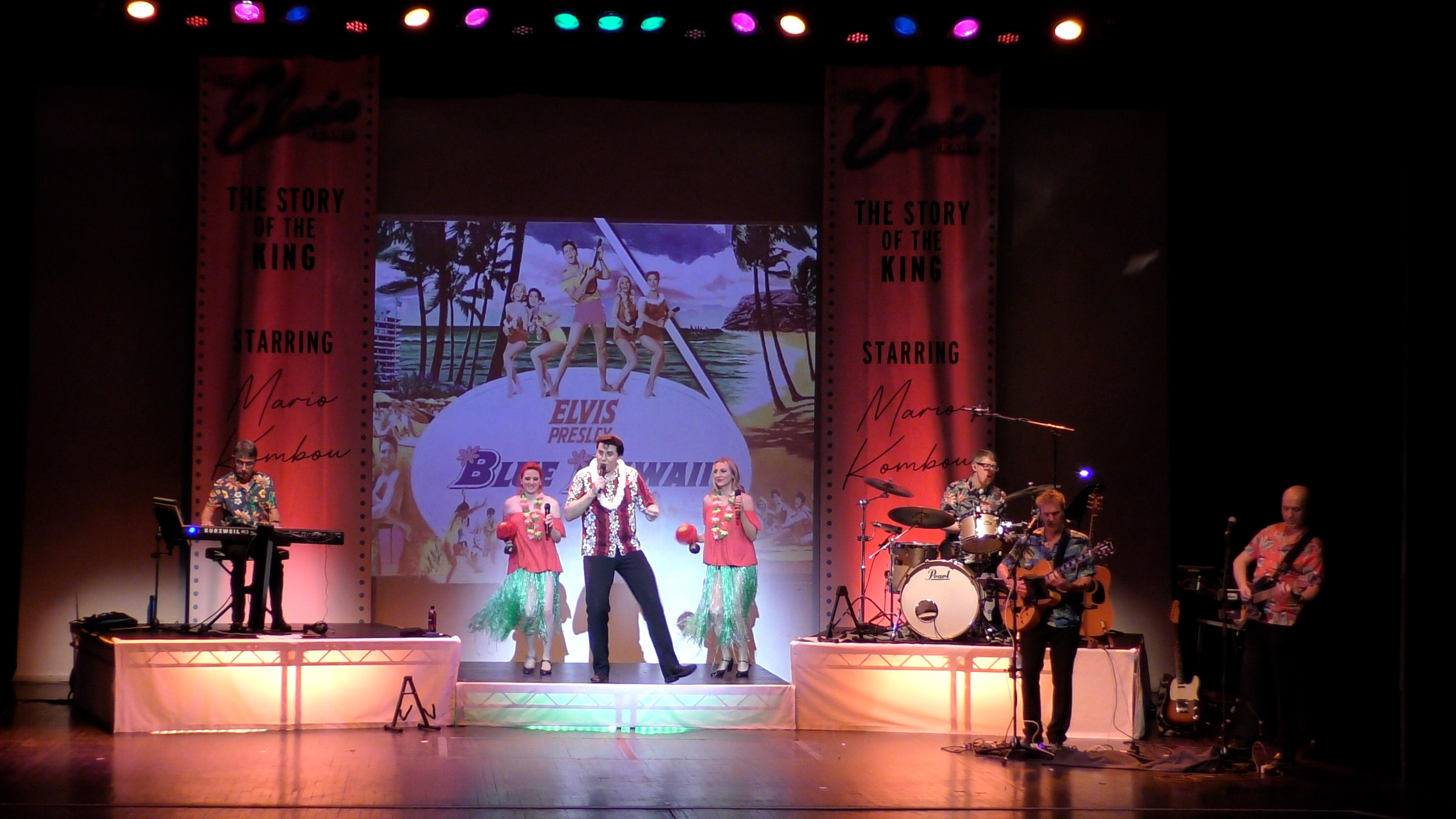 Man singing on stage dressed in Hawaiian shirt 