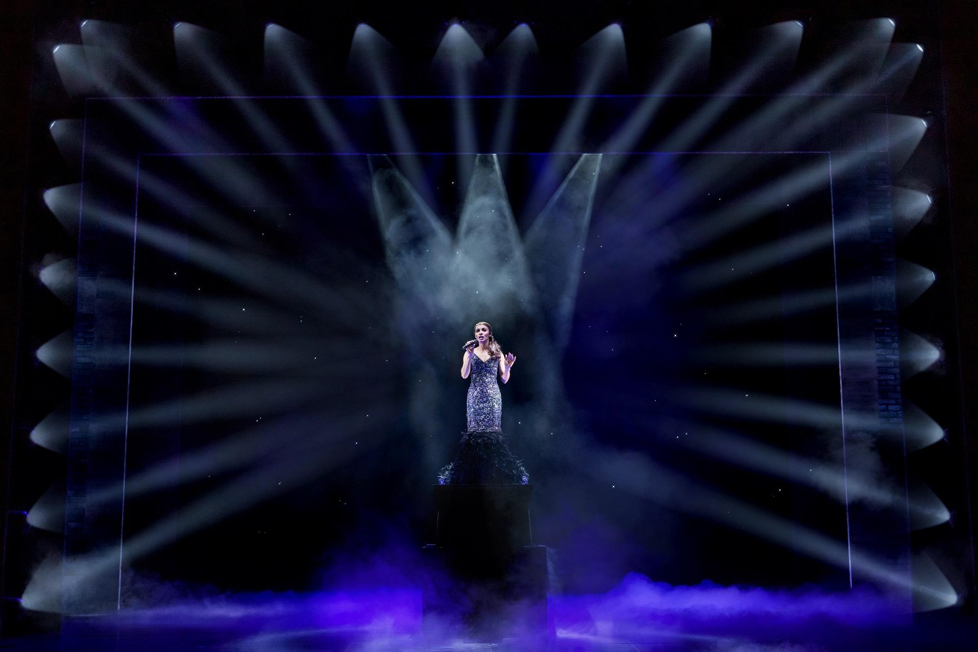 woman singing with lights shining on her