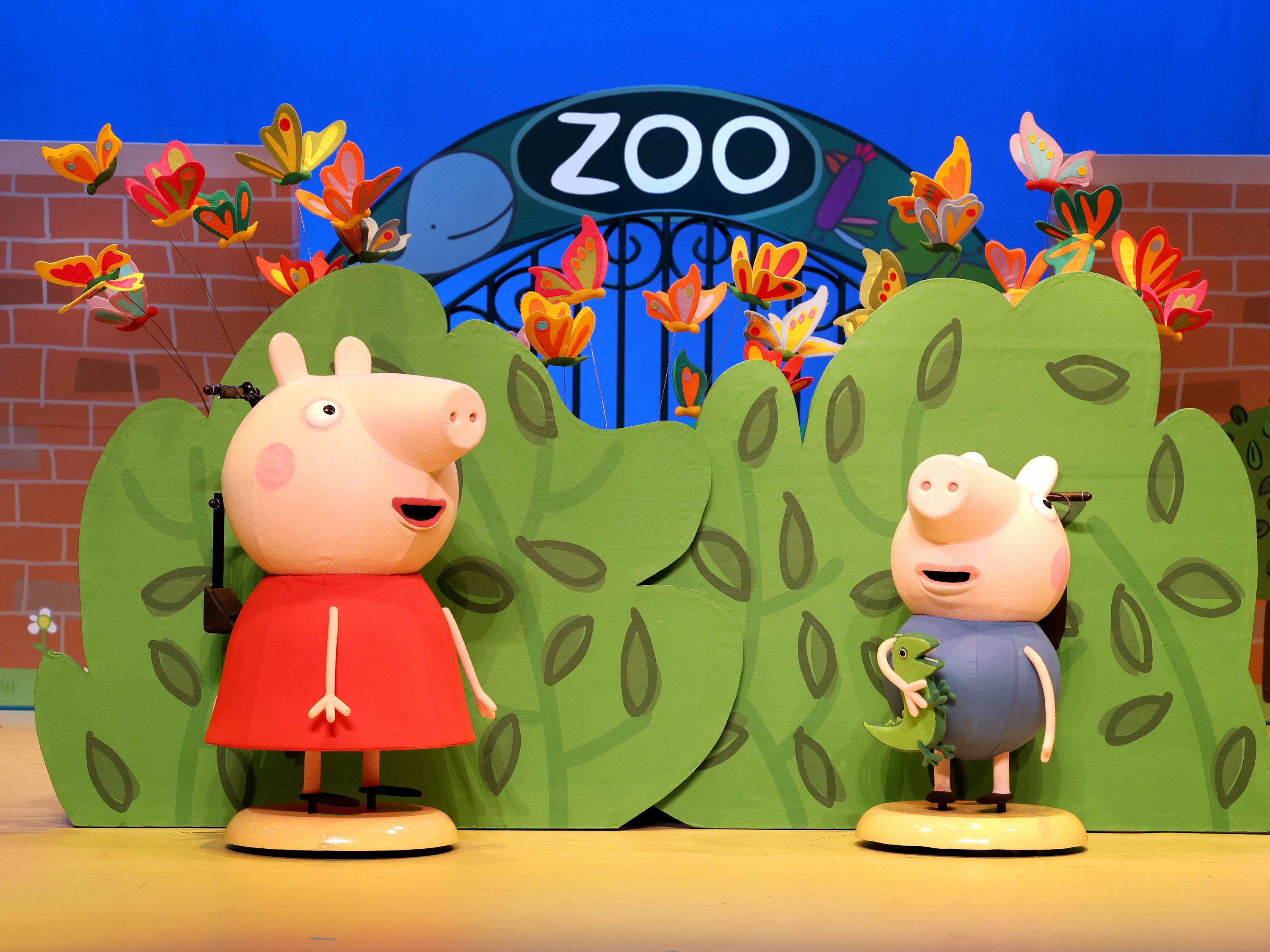 Peppa Pig and George Pig stood in front of a zoo sign