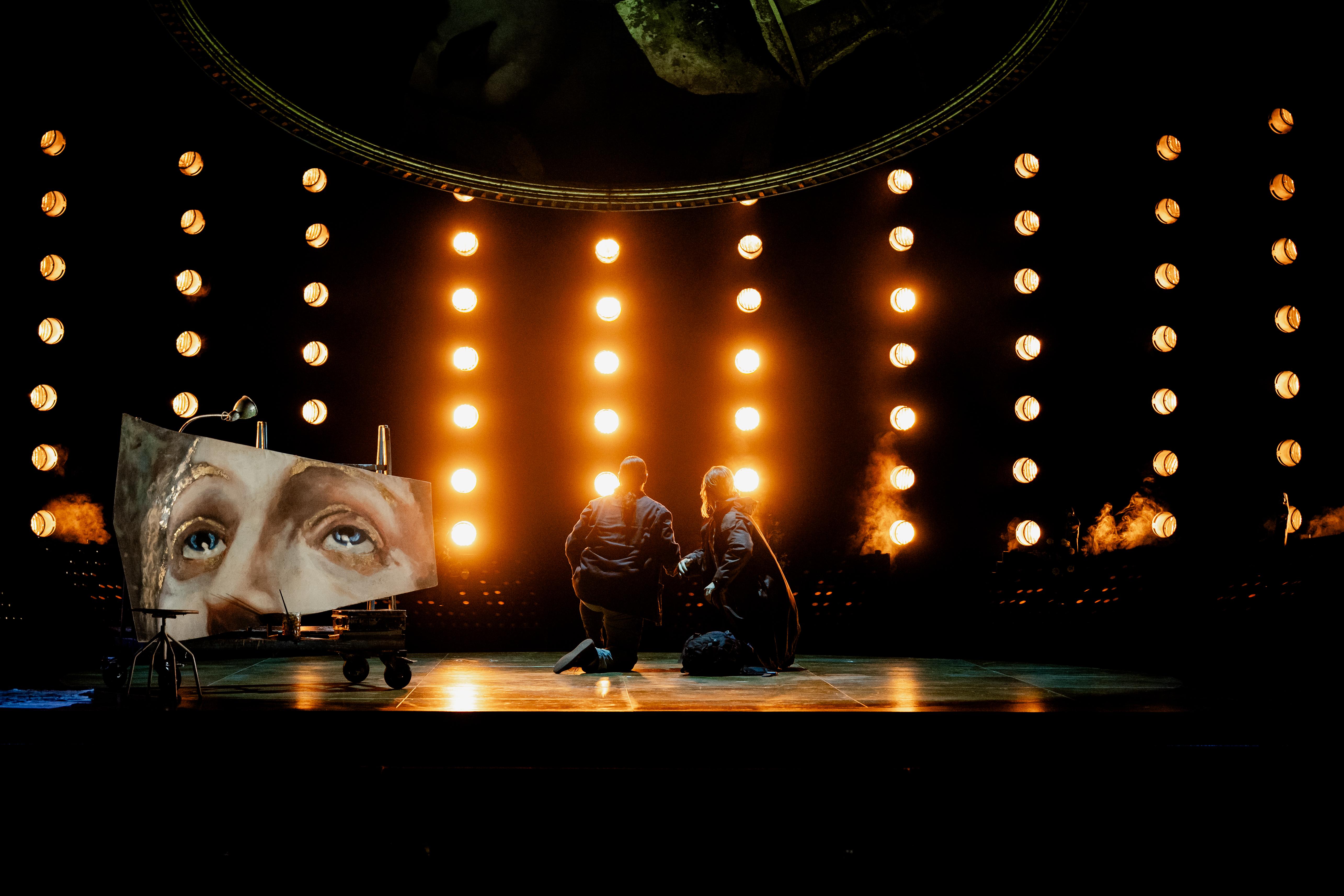 Wide view of stage drenched in light with a large image of a head in the foreground