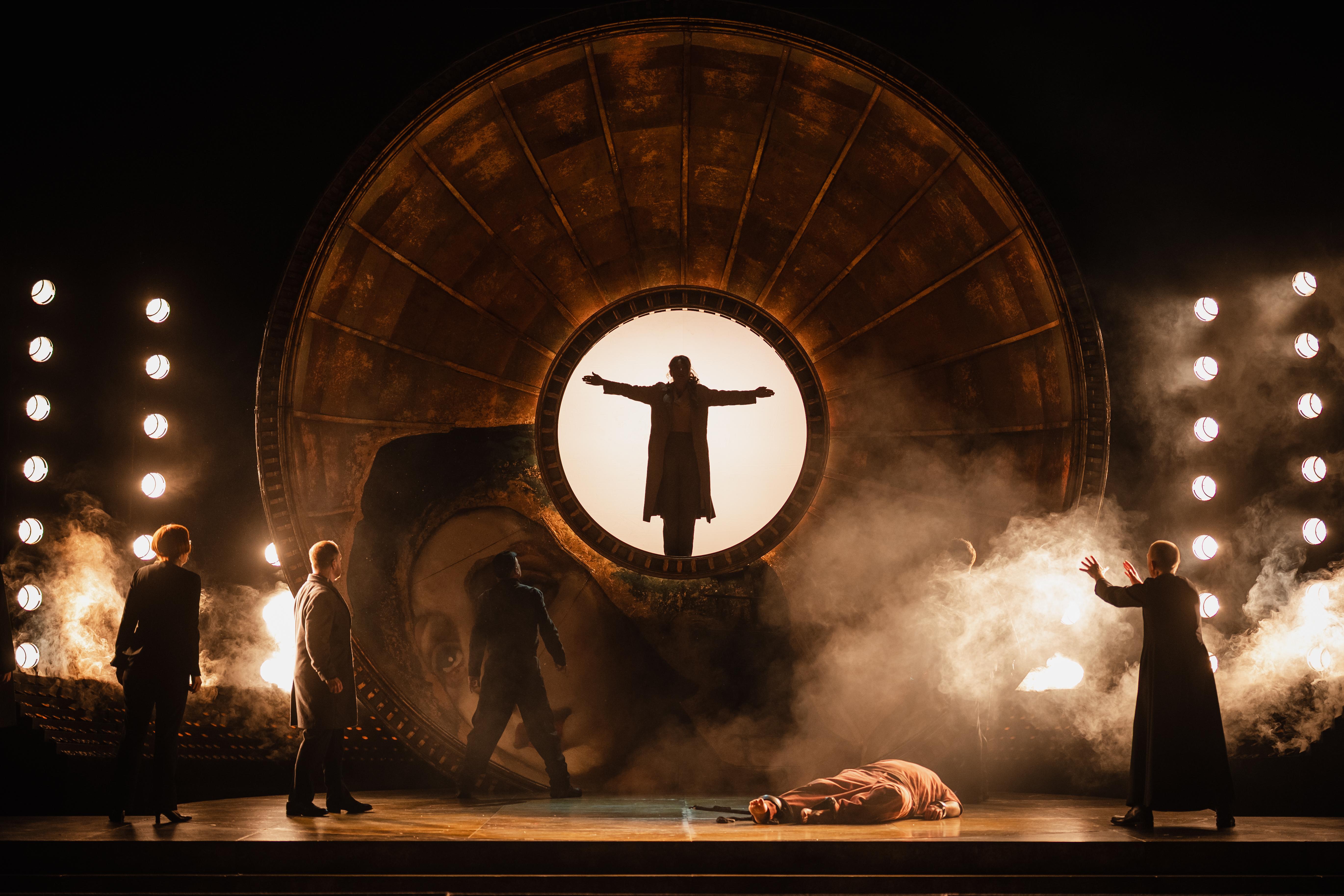 Person stood with arms stretched wide within the centre of circle above the stage