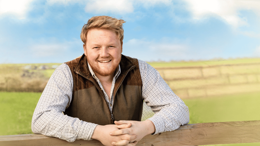 image of a blonde haired man leaning on a fence