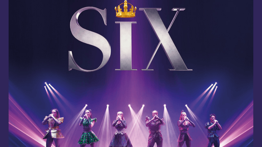 six women in clothing of the Tudor times, but spangly, stand confidently holding microphones. above their head is a large silver SIX and a crown instead of a dot on the i 