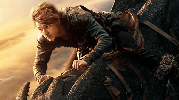 a teenage boy with blond hair rides on the back of dragon through the sky 