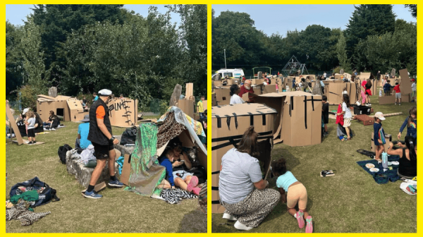 adults and children in a grassy park making dens out of a large cardboard boxes 