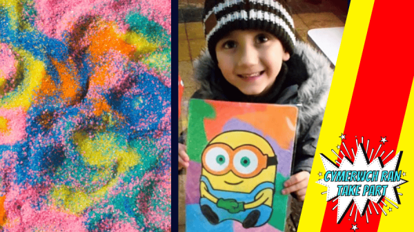 sand in multiple colours and a young boy in a brown and white bobble hat holding a sand art painting of a Minion 