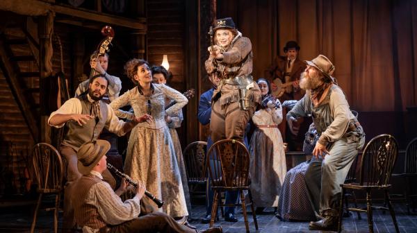 Calamity Jane stood on a chair with a saxophone 