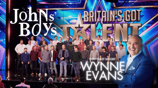 JohnsBoys in choir formation and Wynne Evans' picture on a blue poster 
