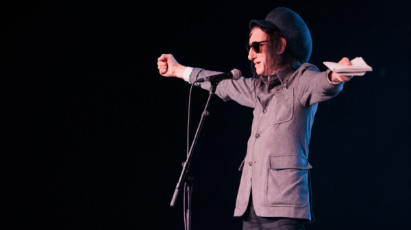 man in hat and glasses holding arms outwards