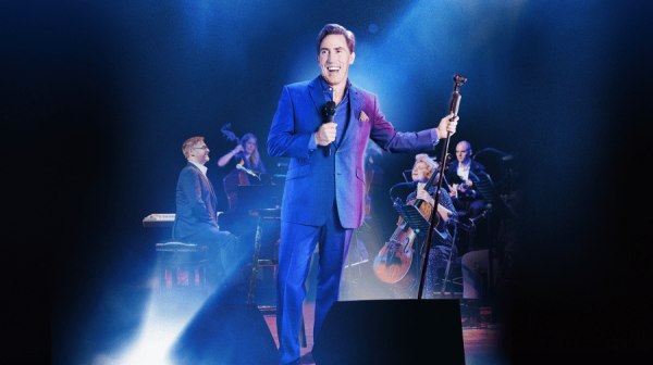 Image of man holding a microphone and leaning on a microphone stand