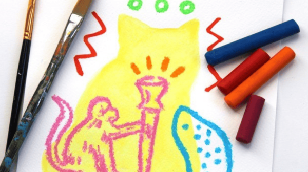 an artist's table - on it are two paint brushes, four crayons, a yellow outline of a cat, inside that outline a drawing of a pink money and an unidentifiable dotted blue creature! 